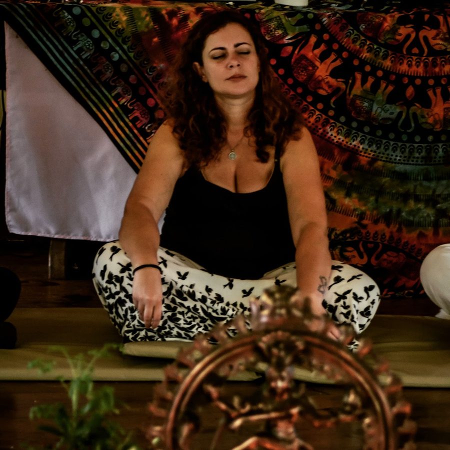 Jaya meditando de pernas cruzadas diante de uma estátua de Shiva Nataraja